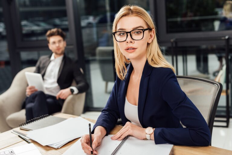 selective focus of businessman looking at businesswoman in eyeglasses that looking at camera at